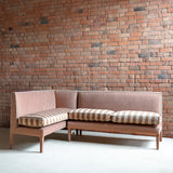 Sectional sofa with striped cushions against a brick wall.