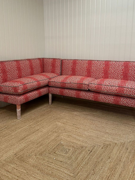 Red patterned sectional sofa in a room with wooden flooring and white walls.