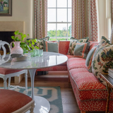 Living room with a red sofa, white table, and patterned chairs.