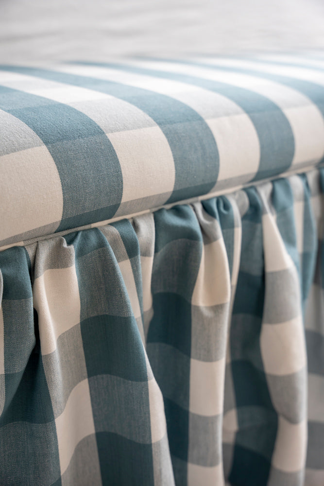 Upholstered ottoman with skirt, and piping around seat