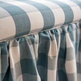 Upholstered ottoman with skirt, and piping around seat