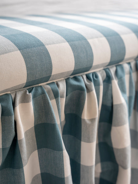 Upholstered ottoman with skirt, and piping around seat