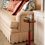 Side profile of the Symington scalloped sofa showing the rolled-arm detail and piping, set next to a small red lacquered side table.
