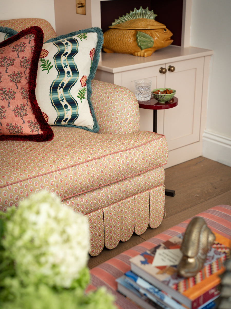 Side profile detail of the Symington sofa showing the rolled arm, contrast piping, and full-length scalloped valance.
