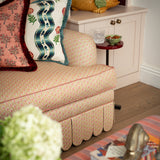 Side profile detail of the Symington sofa showing the rolled arm, contrast piping, and full-length scalloped valance.