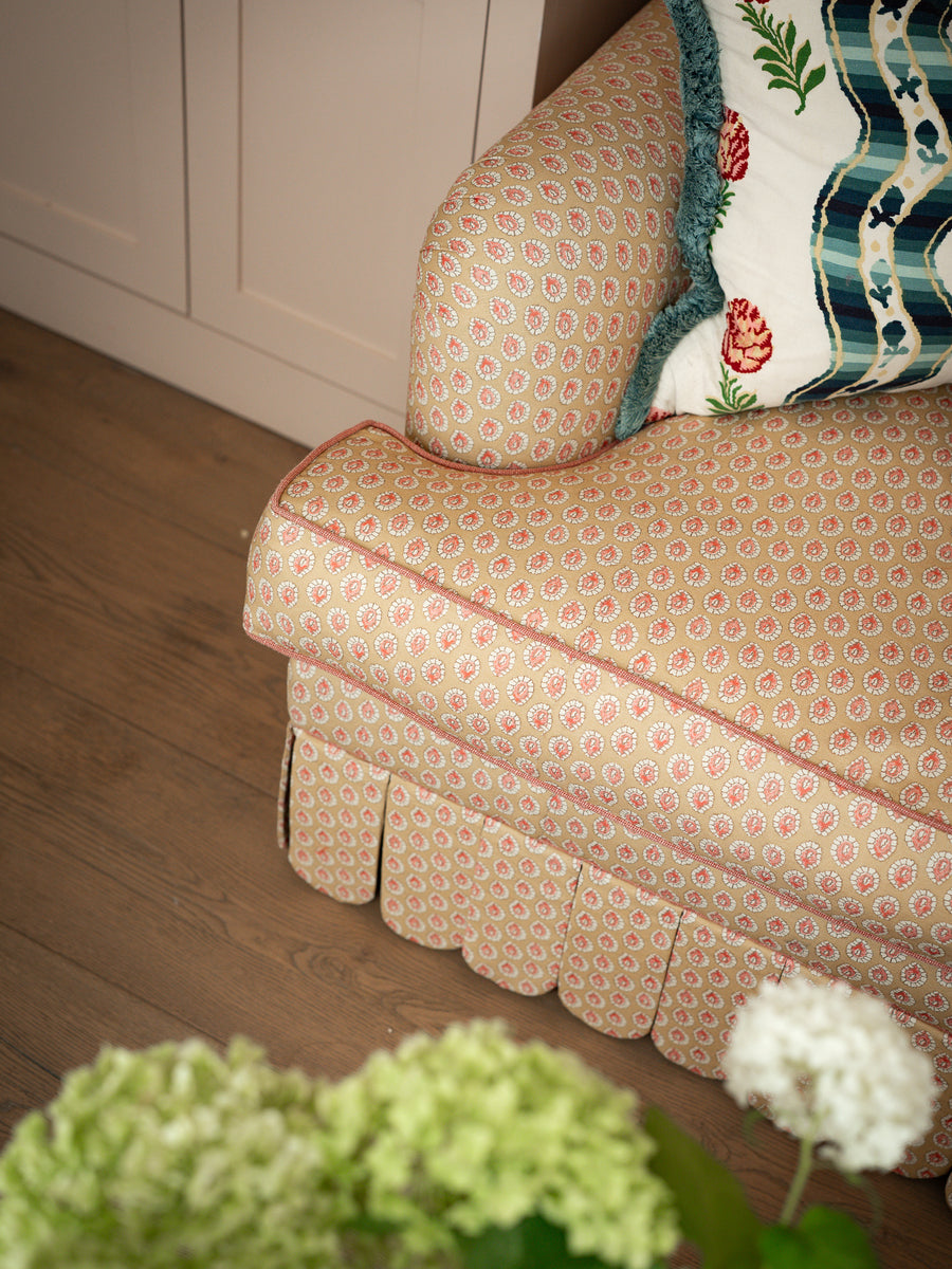 Close-up of the rolled arm cushion and hand-stitched scalloped skirt on the Symington sofa in a domestic setting.