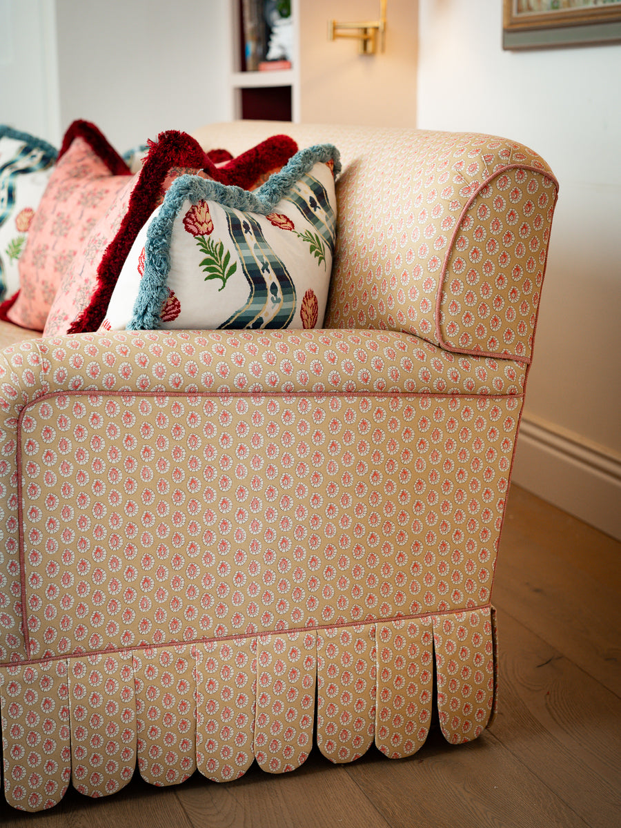 Ground-level view showing the continuous scalloped skirt detailing along the bottom edge of the Symington sofa frame.

