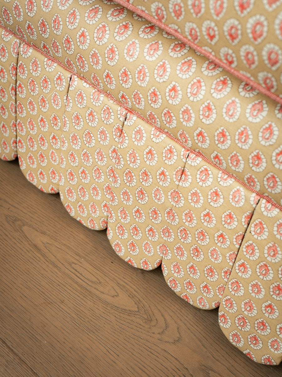 Close-up detail of the hand-piped scalloped skirt and yellow patterned upholstery on the Symington sofa base.