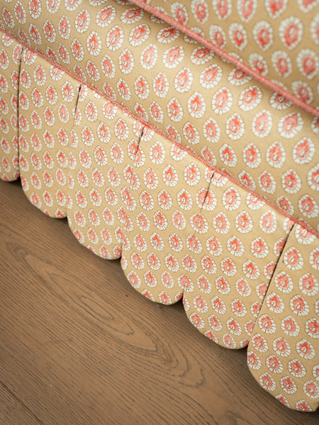 Close-up detail of the hand-piped scalloped skirt and yellow patterned upholstery on the Symington sofa base.