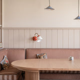 Dining area with wooden table and striped bench against a light-colored wall.