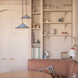 Modern interior with a wooden table, striped sofa, and shelves with decor items.