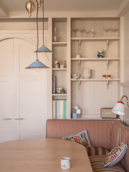 Modern interior with a wooden table, striped sofa, and shelves with decor items.
